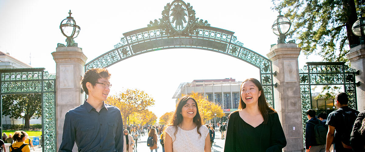 Three students walking through Sather Gate.