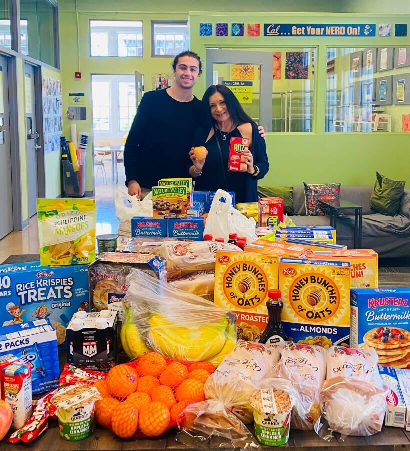 Diana L Lizarraga, wearing a black shirt and student Nick Melamed posing with grocery resources in front of them.