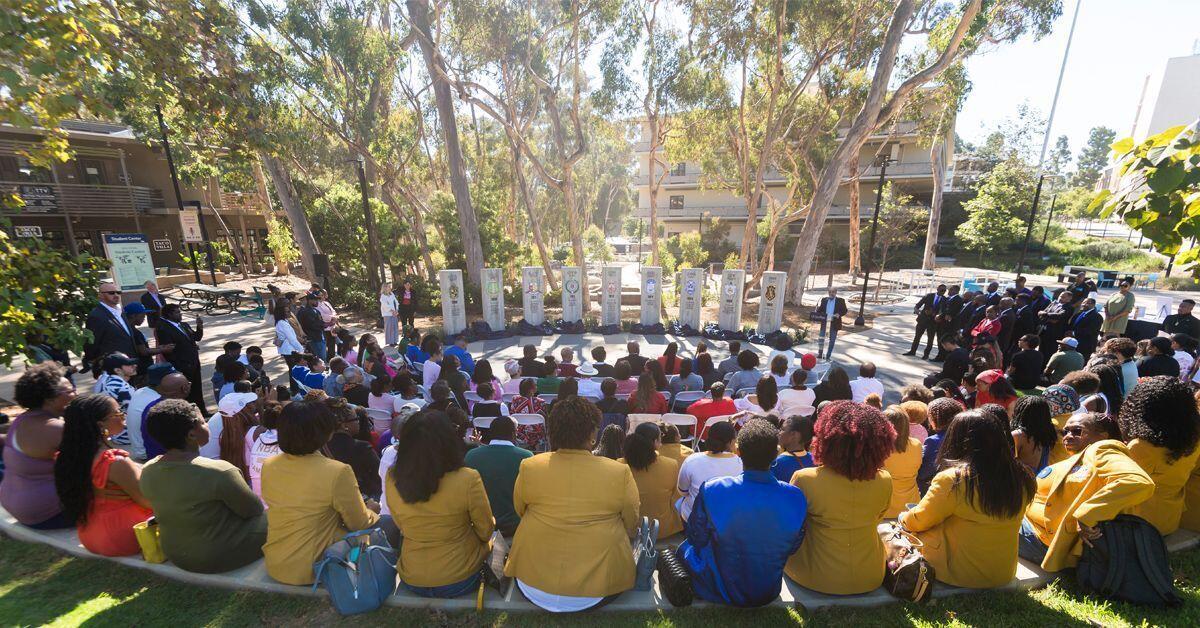 National Pan-Hellenic Council plaza of people sitting in a half circle around cement pillars