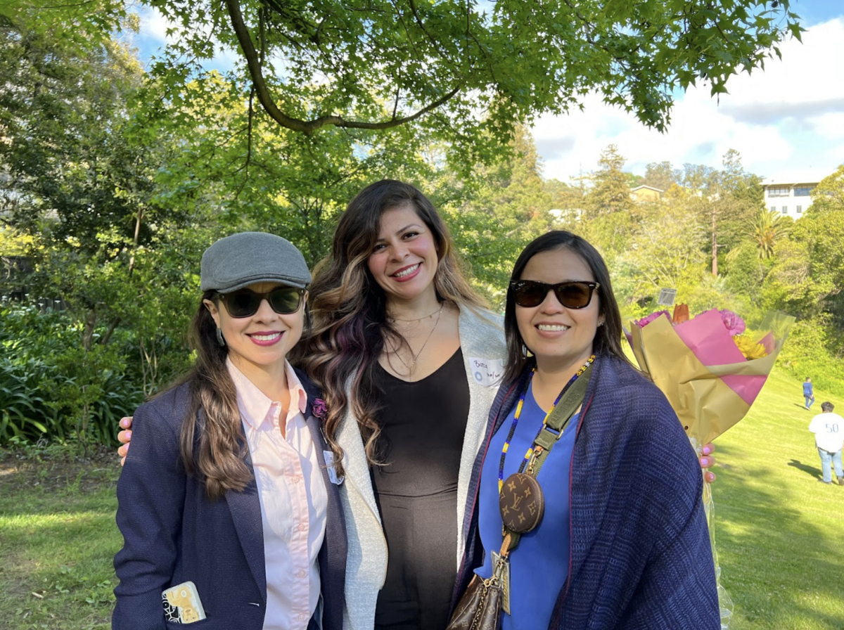 Three woman standing and posing in a field of grass.