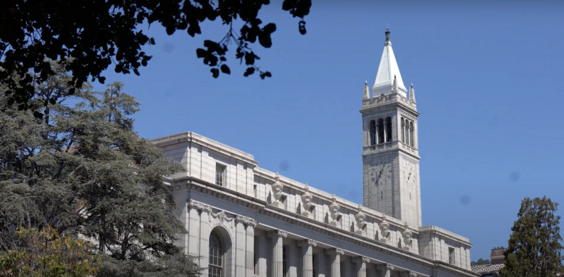 sather tower in the distance and wheeler hall in front with tree leafs on the side