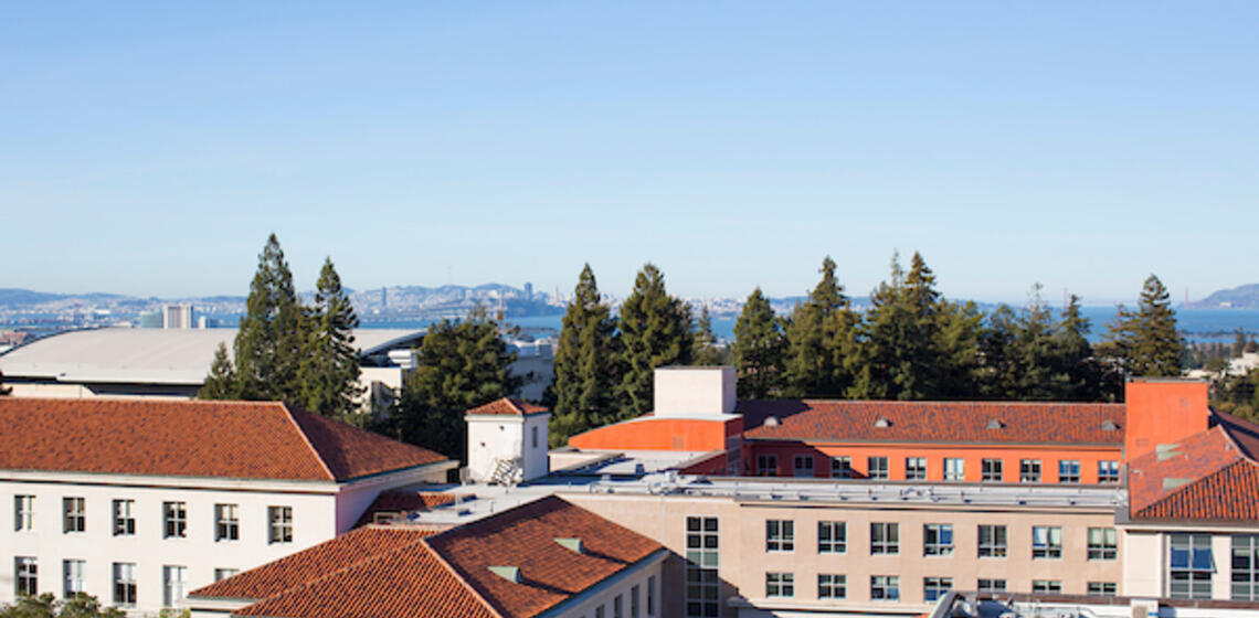 birds eye view of campus buildings with a cloudless blue sky and a glimpse of San Fransisco in the distance